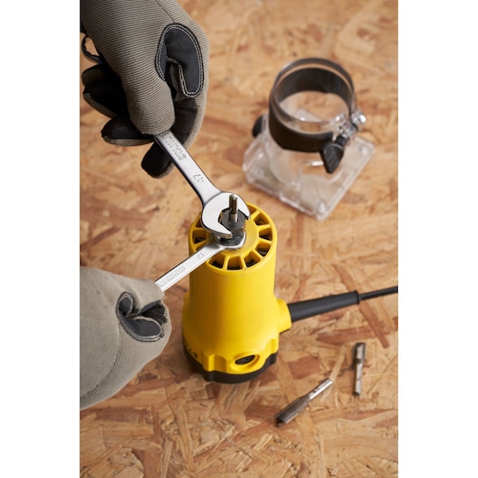 STANLEY ST55 router assembly with wrenches and gloved hands, close-up on tool and accessories on wood surface.