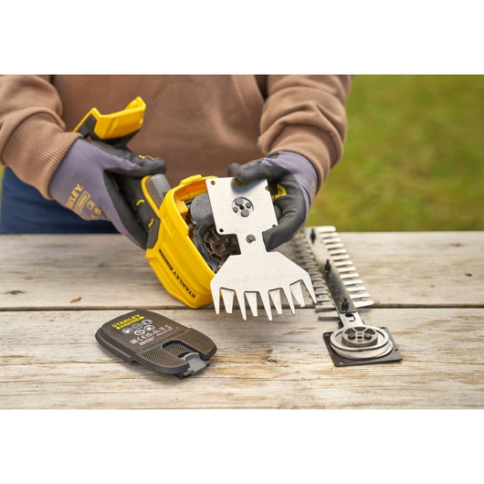 STANLEY STCSS20D1 cordless shear kit being assembled on wooden table outdoors, gloves visible.