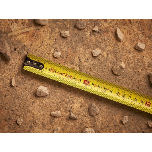 STANLEY STHT0-33561 tape measure photography on a dusty surface with scattered rocks.