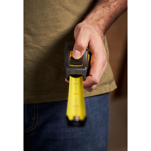 STANLEY STHT0-33561 tape measure held in hand, yellow blade extended, close-up photography.