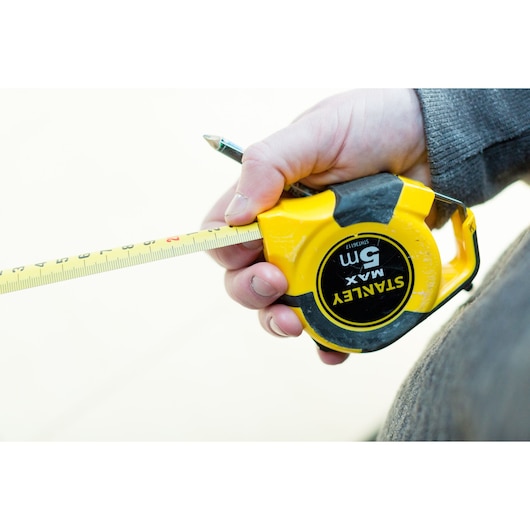 Photo of STANLEY STHT0-36117 yellow tape measure held in hand, tape extended, brand label visible.