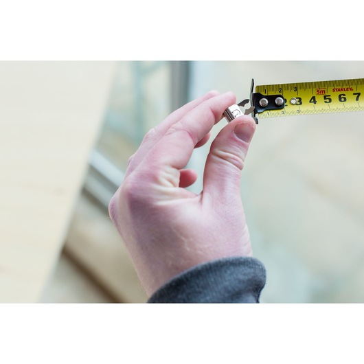STANLEY STHT0-36117 tape measure photography showing close-up measurement of a small metal nut.