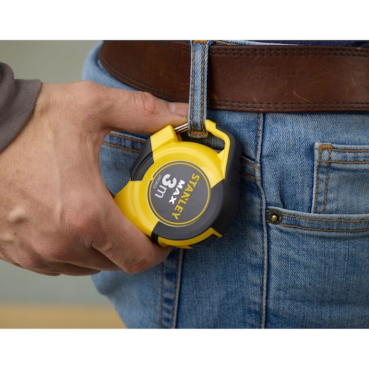 STANLEY STHT0-36121 yellow 3m tape measure held near jeans belt loop.