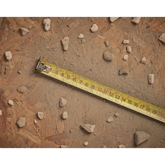STANLEY STHT0-36121 tape measure on a dusty wooden surface with scattered small rocks.