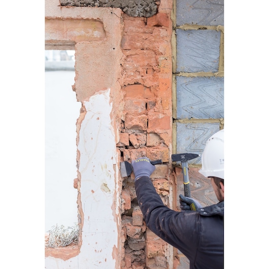 STANLEY STHT0-51910 brick hammer in use at a construction site, worker breaking brick wall.