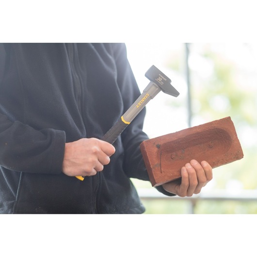 Photo of STANLEY STHT0-54131 club hammer with yellow handle held near a red brick.
