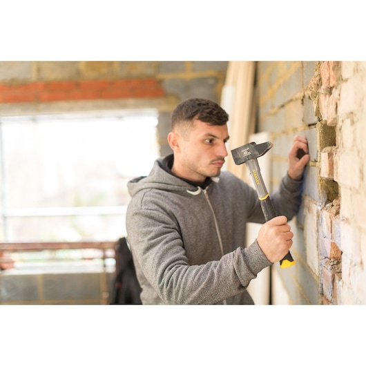 Photo of STANLEY STHT0-54155 hammer in use against a brick wall during construction work.