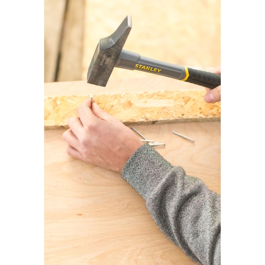 STANLEY STHT0-54160 claw hammer driving nail into wood, close-up photography.