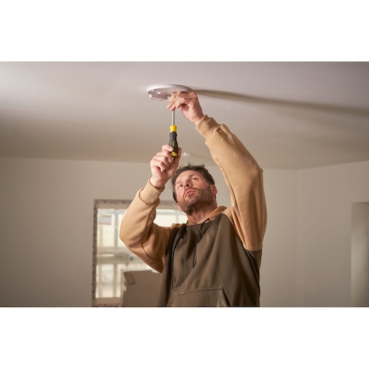 Photo of STANLEY STHT0-70885 hand screwdriver used for ceiling fixture installation, indoor setting.