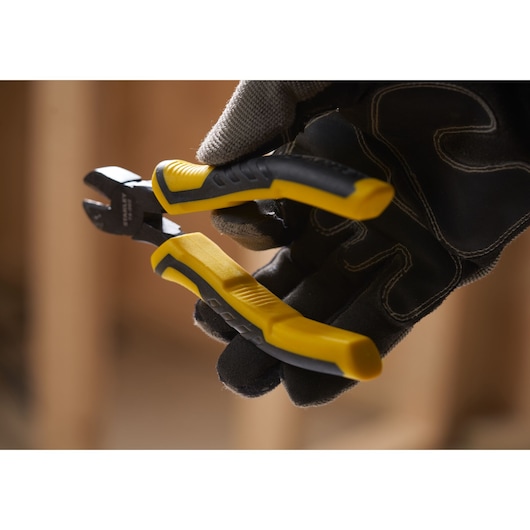 STANLEY STHT0-74362 diagonal cutting pliers with yellow and black handle held by gloved hand, close-up.