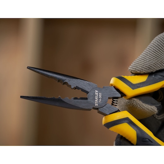 Photo of STANLEY STHT0-74363 pliers with black jaws and yellow-black handles in a gloved hand, close-up.
