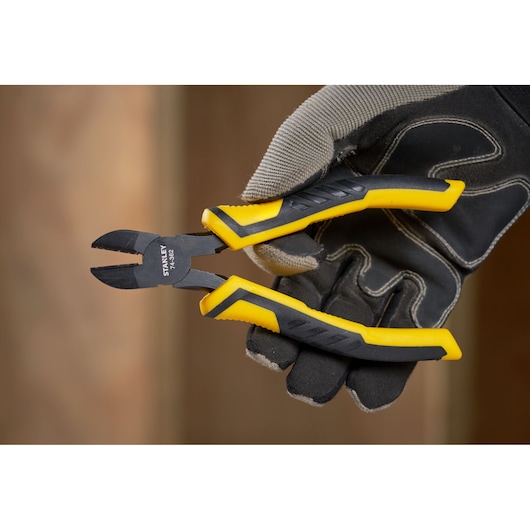STANLEY STHT0-74455 diagonal cutting pliers with yellow and black grips held by gloved hand.