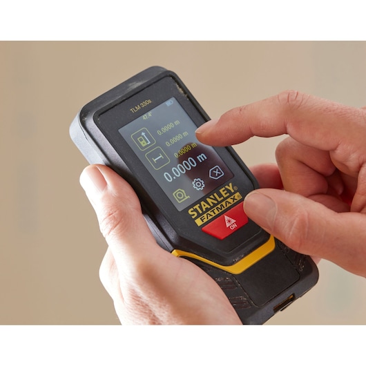 Photo of STANLEY STHT1-77140 laser distance measurer with touchscreen in hand, close-up view.