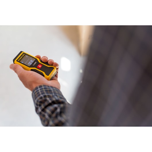 STANLEY STHT1-77409 laser distance measurer held in hand, display visible, photography product shot.