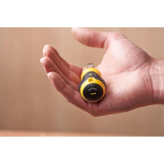 STANLEY STHT16147-0 screwdriver with yellow and black handle held in a hand, close-up front view.