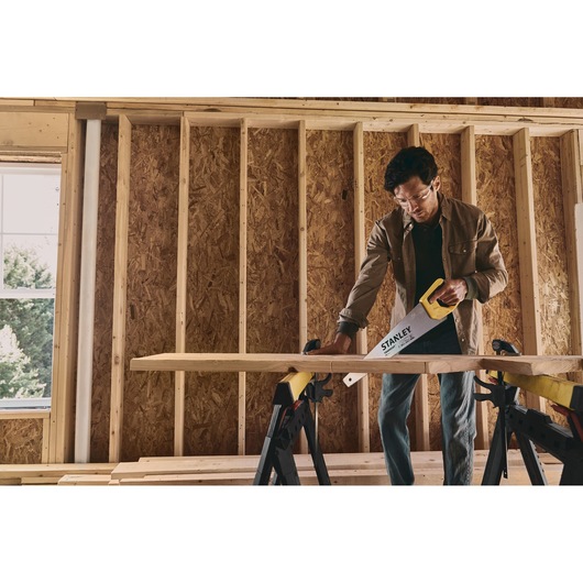 STANLEY STHT20350 hand saw in use cutting wood, photo of product in construction setting.