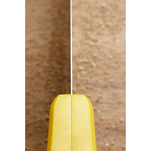 STANLEY STHT20370-1 hand saw close-up, yellow handle and blade, vertical angle on wooden surface.