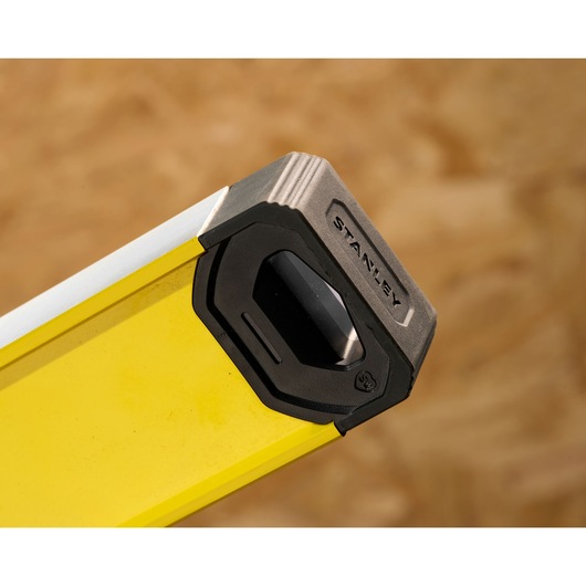Close-up of the end of a yellow STANLEY spirit level with a protective black and silver cap.