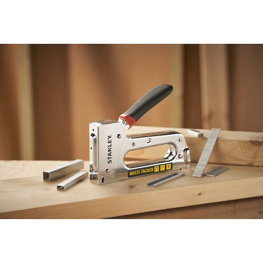 STANLEY STHT6-70410 Multi-Tacker stapler with black handle, shown with staples on wood surface.