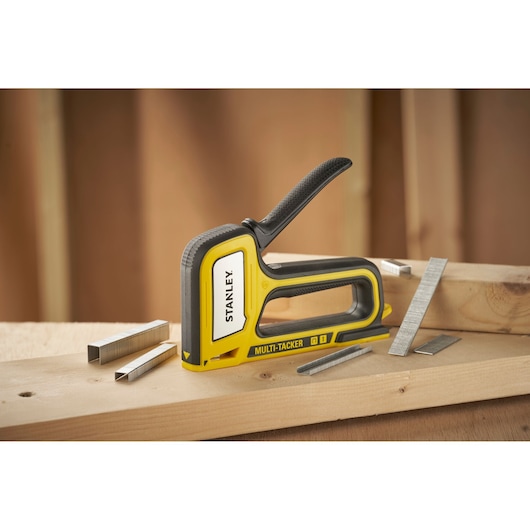 Stanley STHT70440-0 multi-tacker stapler with staples on wood surface, side angle.