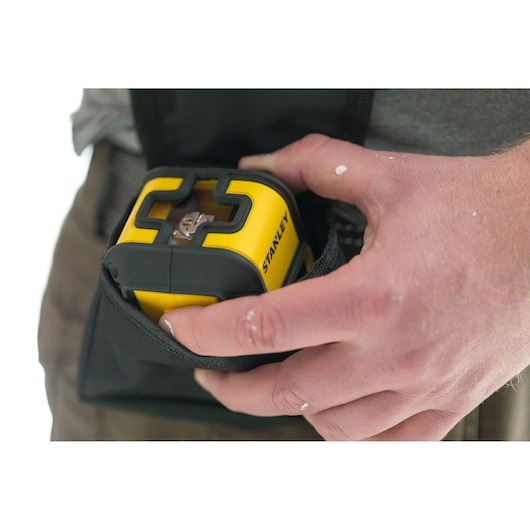 STANLEY STHT77498-1 yellow laser level being held and placed in a black pouch, close-up photography.