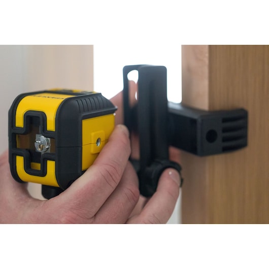 STANLEY STHT77498-1 yellow and black laser level being mounted on wooden surface, close-up.