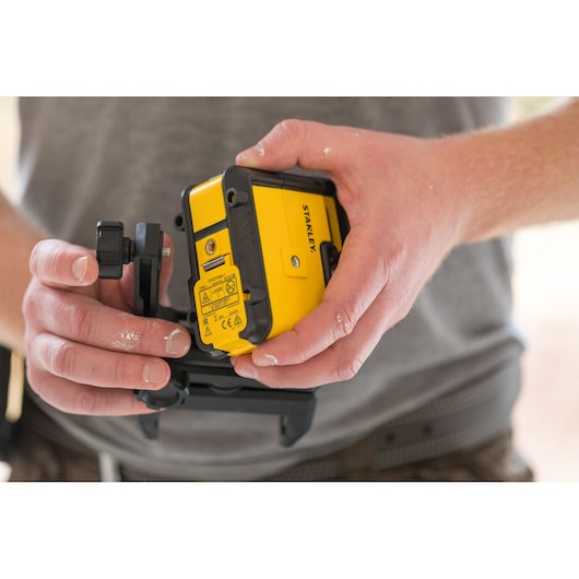 Photo of STANLEY STHT77504-1 yellow and black laser level held in hands, construction context.