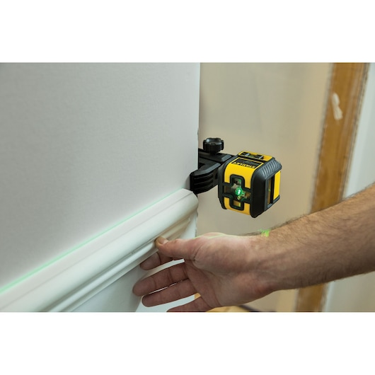STANLEY STHT77592-1 laser level tool projecting green line on wall during baseboard installation.