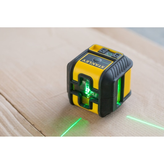 STANLEY STHT77592-1 laser level showing green beams, compact yellow and black design, angled view.