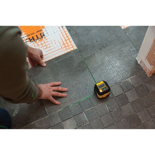 STANLEY STHT77592-1 laser level used for tile alignment on a gray tiled floor during installation.