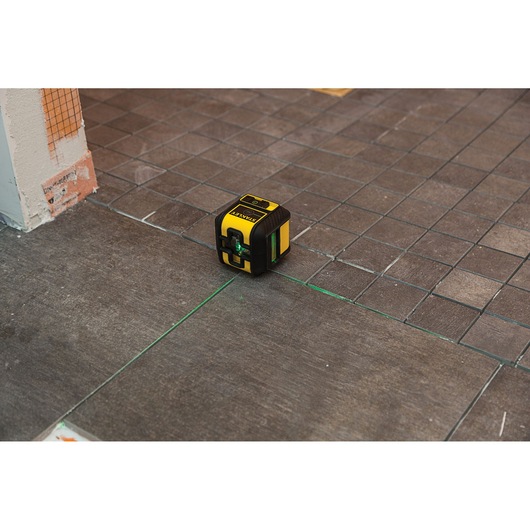 STANLEY STHT77592-1 laser level projecting green lines on tiled floor.