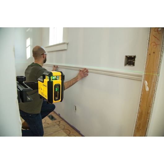 Photo of STANLEY STHT77594-1 laser level mounted, projecting green line for wall trim installation.