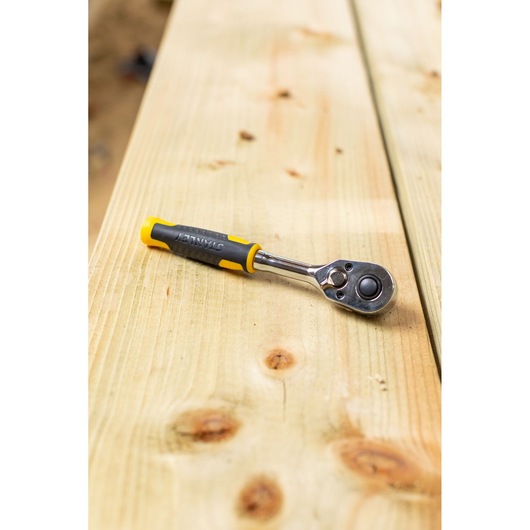 STANLEY STMT82663-0 ratchet wrench with yellow and black handle on wood surface.