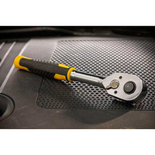 STANLEY STMT82665-0 ratchet wrench with yellow and black handle on a perforated surface.