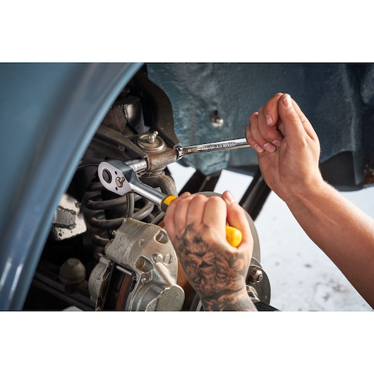 STANLEY STMT82672-0 ratchet and socket set used on car suspension, close-up of hands with tools.