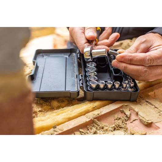 STANLEY STMT82672-0 socket set with ratchet in black case on a worksite, hands selecting a socket.