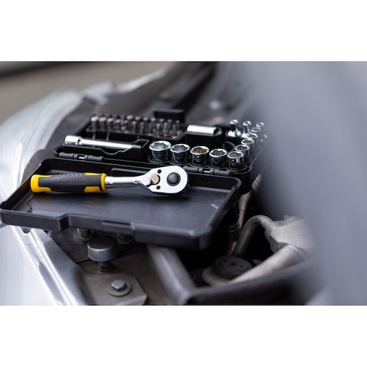 STANLEY STMT82672-0 ratchet and socket set on black tray, shown in automotive repair setting.