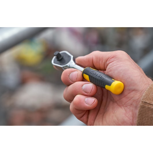 Photo of STANLEY STMT82672-0 compact ratchet with yellow and black handle held in hand, socket drive visible.