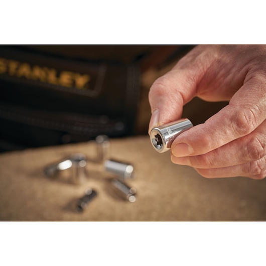 Photo of STANLEY STMT86105-0 chrome socket held in hand, with other sockets on a workbench.
