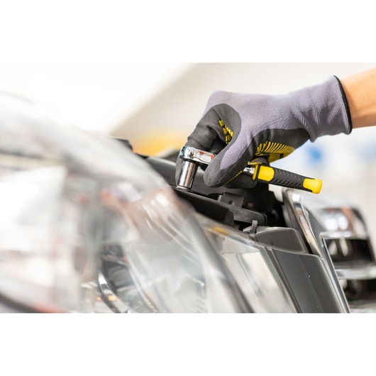 STANLEY STMT86107-0 ratchet tool in use on car headlight, close-up photography.