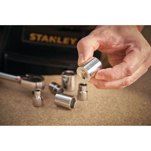 Photo of STANLEY STMT86305-0 socket set pieces on a work surface, one socket held in hand.