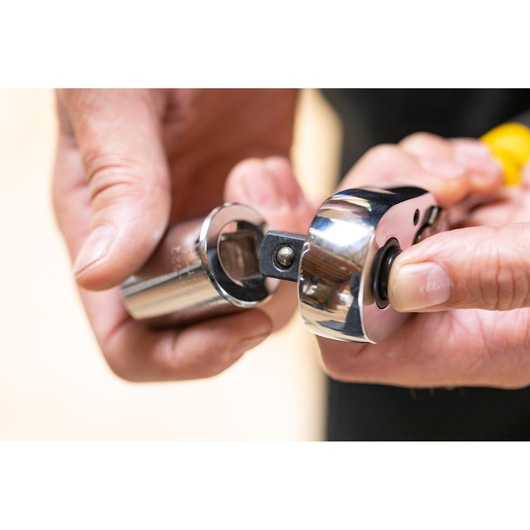 Close-up of STANLEY STMT86520-0 socket wrench and socket, hands attaching parts, tool category.