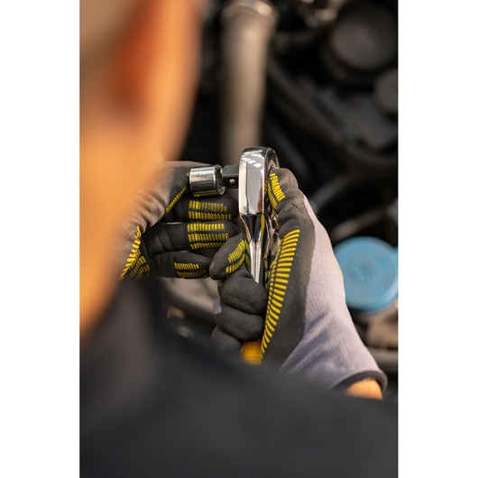 Photo of STANLEY STMT86522-0 ratchet held by gloved hands, close-up view, automotive setting.