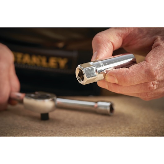 Photo of STANLEY STMT88942-0 chrome socket tool held in hand, with ratchet wrench on table.