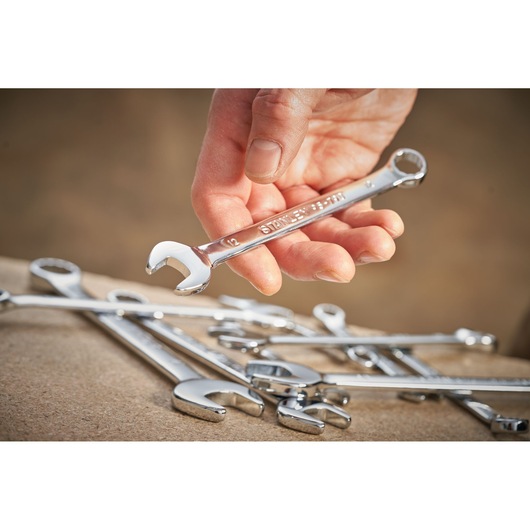 Photo of STANLEY STMT95790-0 combination wrench held in hand, with other chrome wrenches on a workbench.