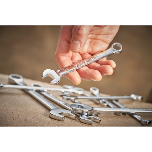 STANLEY STMT95909-0 combination wrench held in hand, with several chrome wrenches on a work surface.