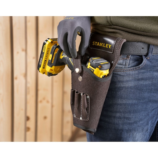 STANLEY STST1-80118 leather tool holster on belt, holding yellow power tools, close-up view.