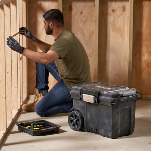 STANLEY STST33090-1 rolling tool box in workshop with tray and user measuring wood studs