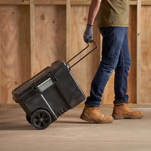 STANLEY STST33090-1 rolling toolbox being pulled by a person in work boots, side view indoors.