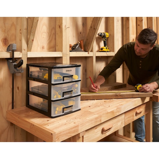 STANLEY STST40712-1 plastic drawer organizer on wooden workbench, filled with tools, in workshop setting.